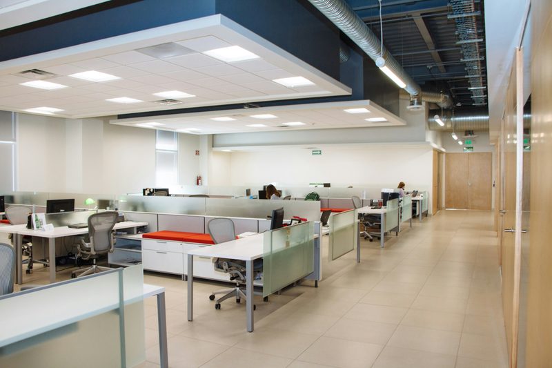 Open-plan commercial office interior with workstations and glass partitions